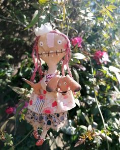 a doll hanging from a tree with flowers in the background