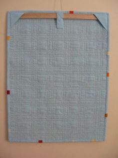 a blue piece of cloth hanging on a wall next to a wooden board with pegs