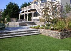 an outdoor patio with steps leading up to the back of a large house and lawn area