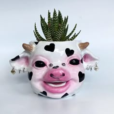 a ceramic cow planter with hearts on it's face and a succulent in its mouth