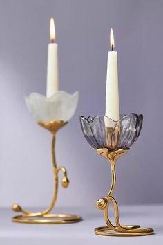 two candles are sitting next to each other on a table with one candle in the middle