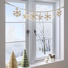 a window sill with snowflakes hanging from it's sides and a small toy dog sitting on the windowsill