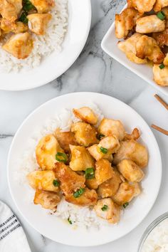 two plates with chicken and rice on them next to chopsticks, sauce and spoon