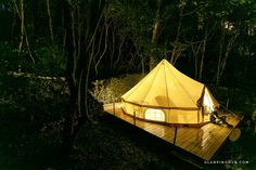 a tent is lit up in the woods