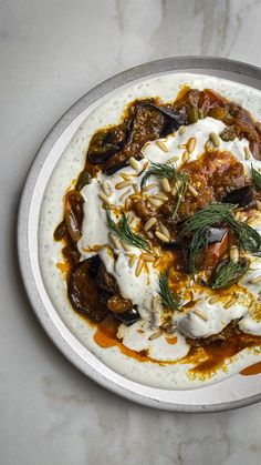 a white plate topped with lots of food on top of a marble countertop next to a knife and fork