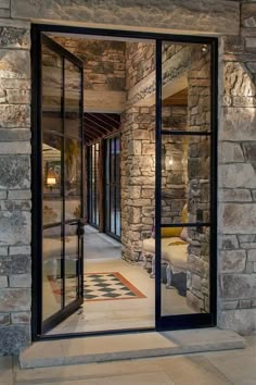 an open glass door leading into a stone building