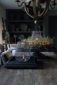 a birdcage is sitting on top of a wooden table with candles in it