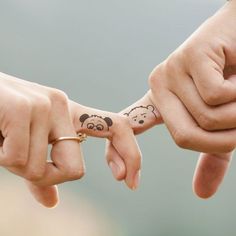 two people holding hands with tattoos on their fingers and one has a teddy bear tattoo