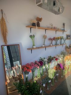 flowers are arranged in vases on the wall next to a mirror and other items