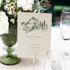 there is a table setting with place cards and flowers in the vase on the table