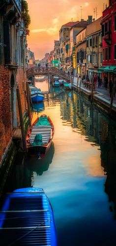 boats are parked on the water in front of buildings and a bridge at sunset or dawn