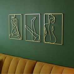 three metal art pieces on the wall above a couch in a green room with a yellow chair