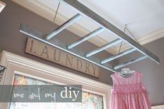 a pink dress hanging on a clothes line in front of a sign that says laundry