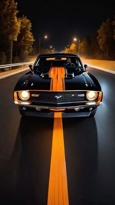 a black and orange muscle car driving down the road with its lights on at night