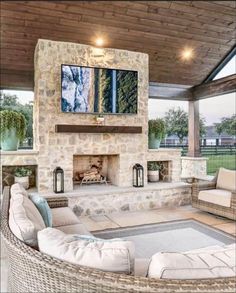 an outdoor living room with stone fireplace and seating