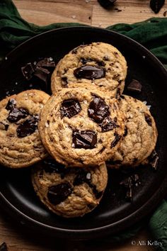 four chocolate chip cookies on a black plate