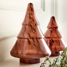 two copper colored vases sitting on top of a white counter next to a plant