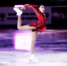 a female figure skating on the ice in a red dress and white shoes with her legs spread out