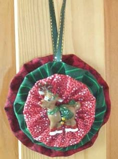 a christmas ornament hanging on a wooden door with red and green ribbon around it