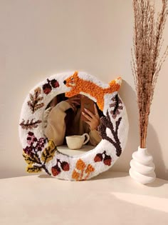 a woman taking a selfie in a mirror next to a vase with dried flowers