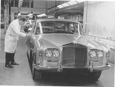 an old photo of a car being worked on by a man in a white coat