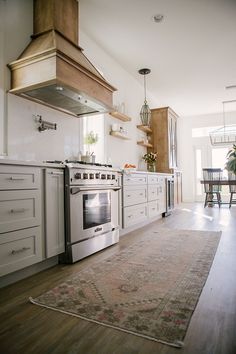 a kitchen with an oven, stove and dining room table in the backround