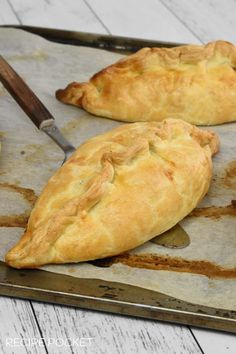 two pieces of bread sitting on top of a baking sheet with a knife next to it