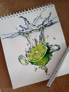 a drawing of a lime with water splashing on it next to a pen and paper