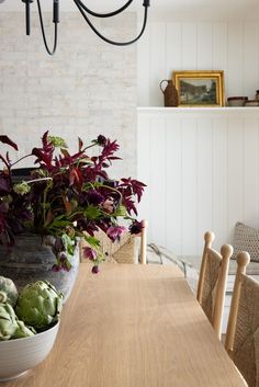 a wooden table topped with lots of green vegetables next to a potted plant on top of a hard wood floor