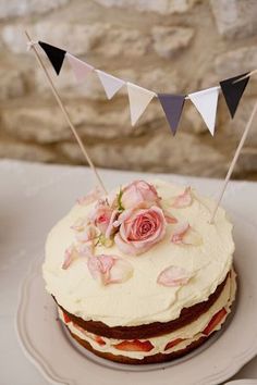 a cake with white frosting and pink flowers on top is sitting on a plate