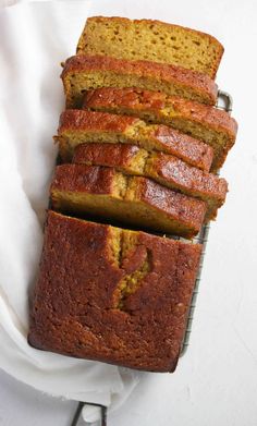 sliced loaf of banana bread sitting on top of a cooling rack next to a white towel