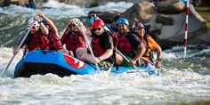 a group of people riding on the back of a raft down a river