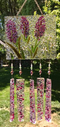 some flowers are hanging from a chain in the middle of a grassy area with trees and grass