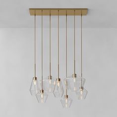 five clear glass pendants hang from a brass ceiling light fixture in an empty room