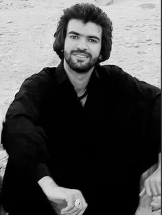 black and white photograph of a man sitting on the ground with his hand in his pocket