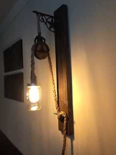 a mason jar hanging from the side of a wall next to a light on a rope