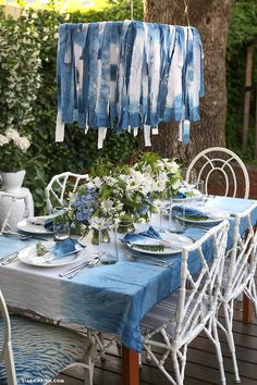 a table with blue and white cloths hanging from it's ceiling, set for dinner