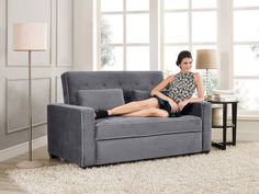 a woman sitting on top of a gray couch