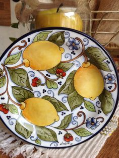 a plate with lemons painted on it next to a candle and some other items