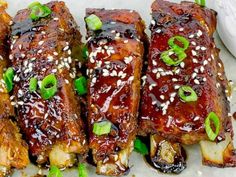 ribs covered in sauce and green onions with sesame seeds on the side, ready to be eaten