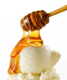 a scoop of ice cream with honey on top and syrup pouring over the top to it