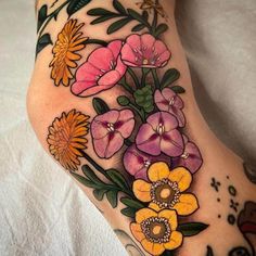 a close up of a person's leg with flowers on it and an insect in the background