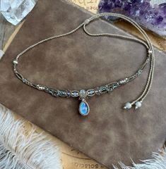 a necklace with a blue stone hanging from it's side on a piece of cloth