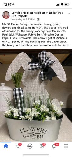 an easter bunny planter with white flowers in it and a black bow on top