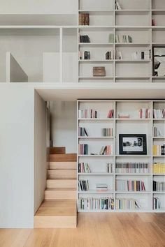 a bookshelf filled with lots of books next to a stair case