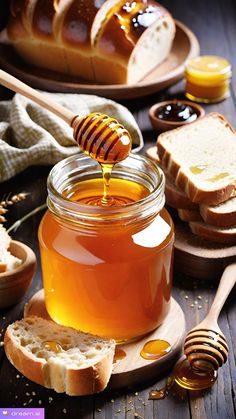 a jar of honey sitting on top of a wooden table next to bread and butter