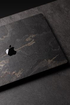 an apple logo is displayed on the back of a macbook pro with marbled surface