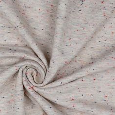 a white fabric with multicolored dots is shown in close up view on the surface