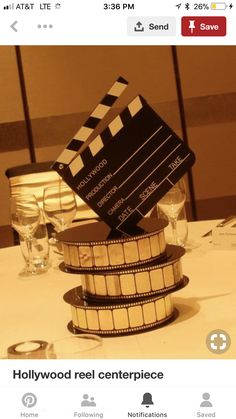 a table topped with a stack of film reels next to wine glasses and silverware