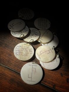 several white buttons with writing on them sitting on a wooden table next to each other